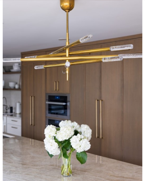 Luxury home design detail – gold starburst chandelier with textured glass rods illuminating a modern kitchen 
